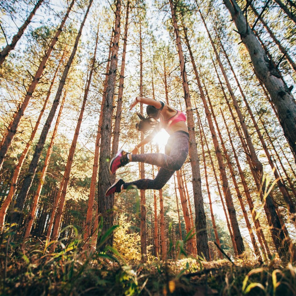 Frau macht Luftsprung im Wald